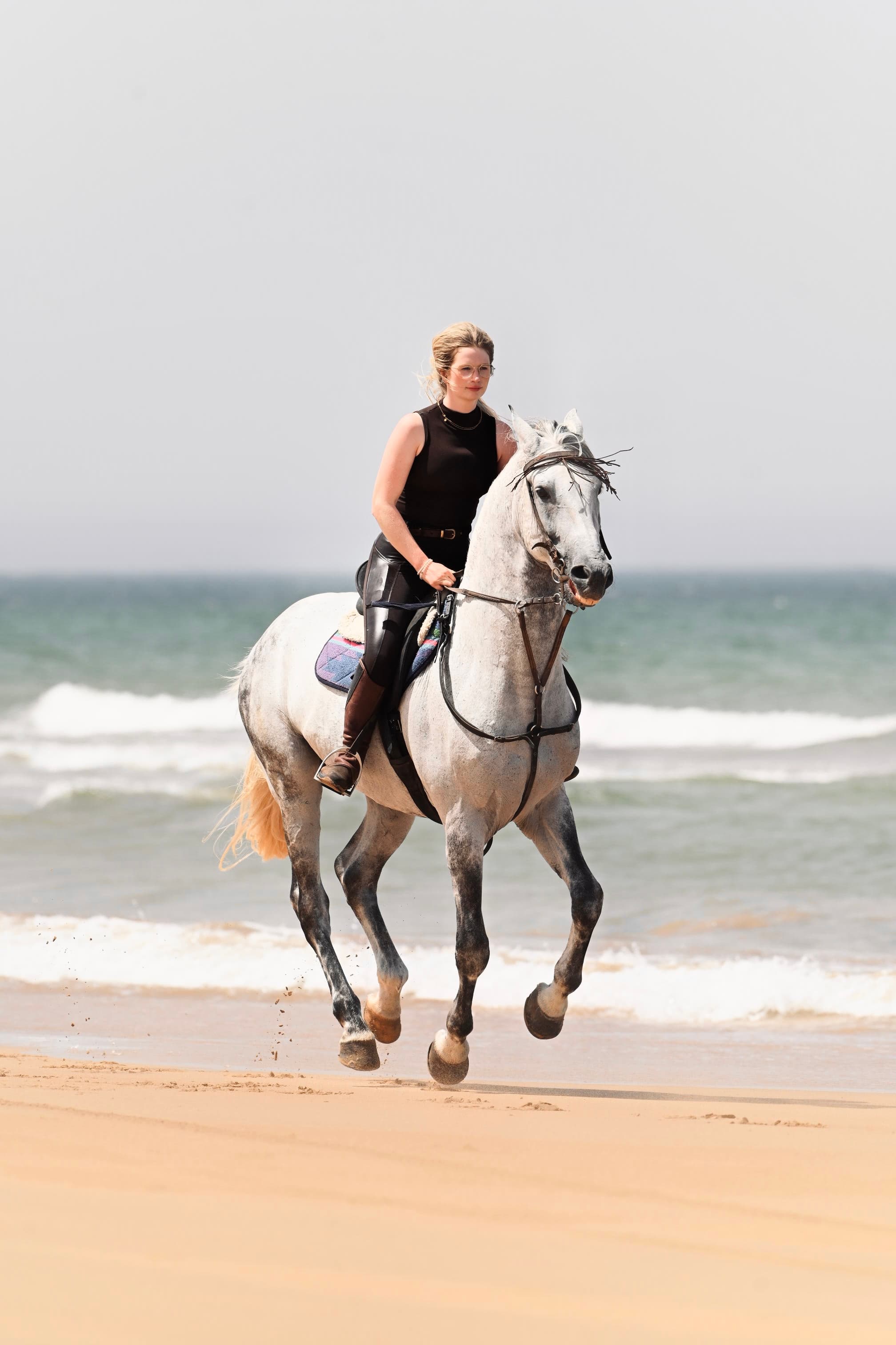 Rider on a white horse cantering along Essaouira beach