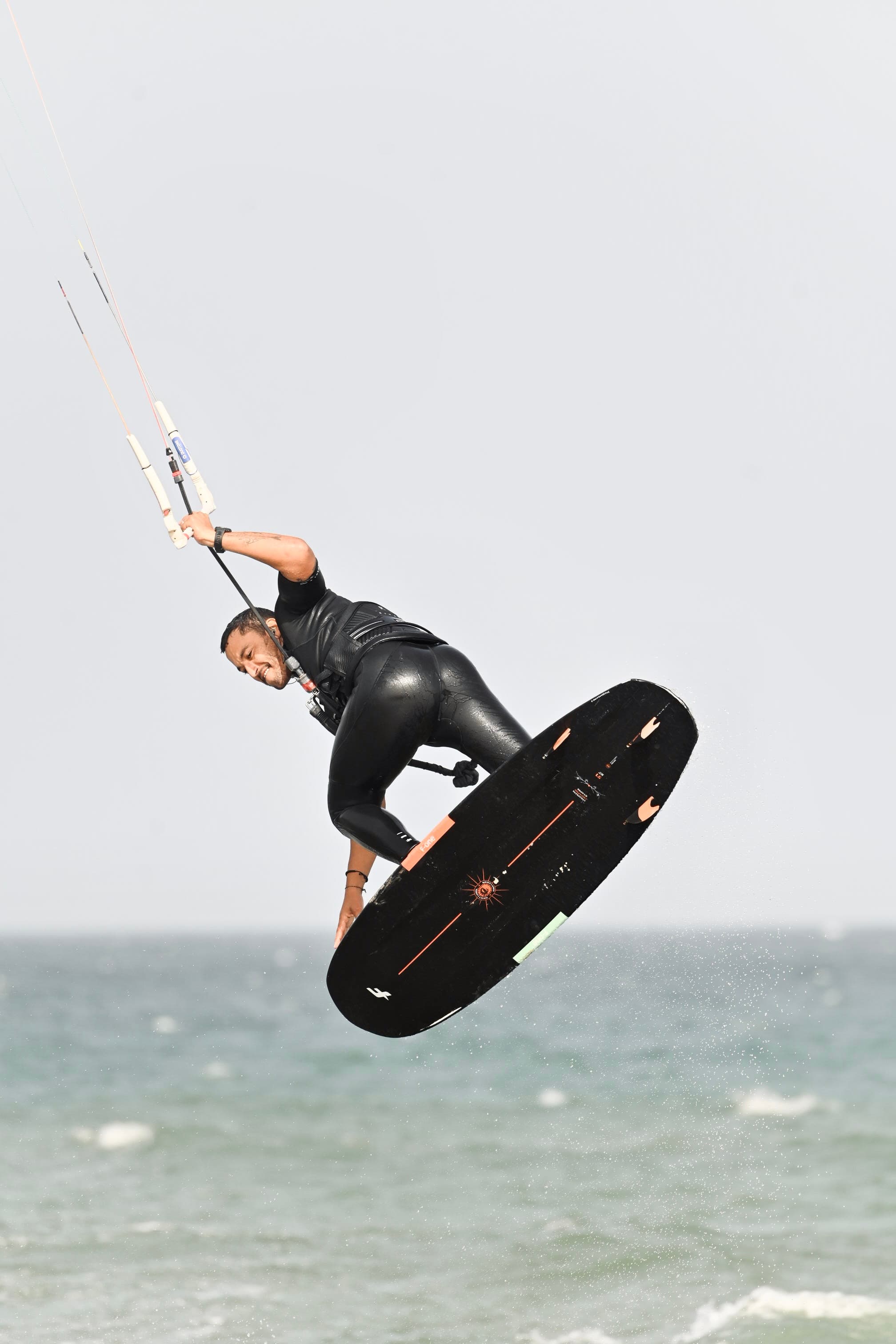 Kitesurfer grabbing his board mid-air above the waves in Essaouira