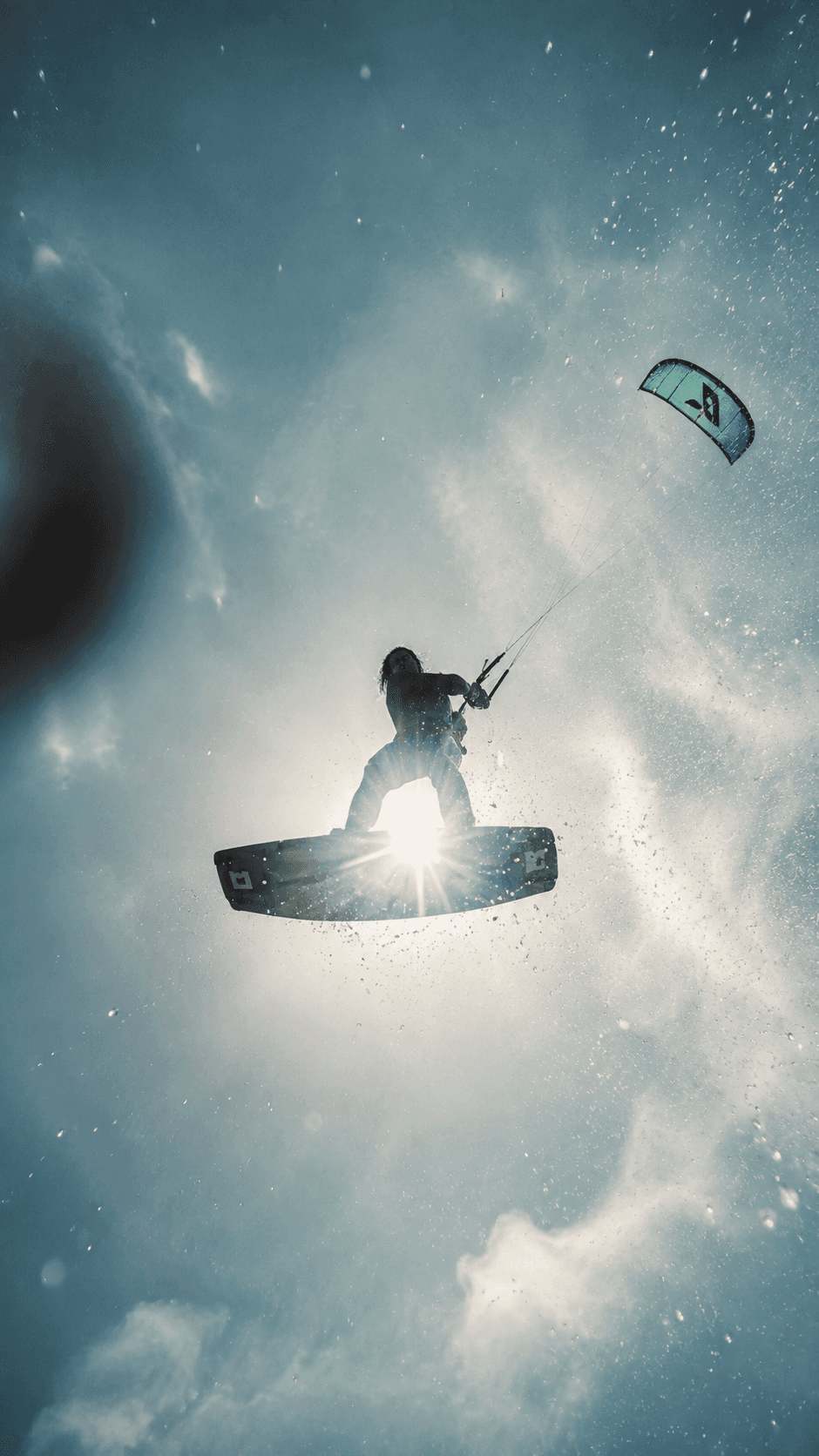 Kitesurfer silhouetted mid-air against the sun