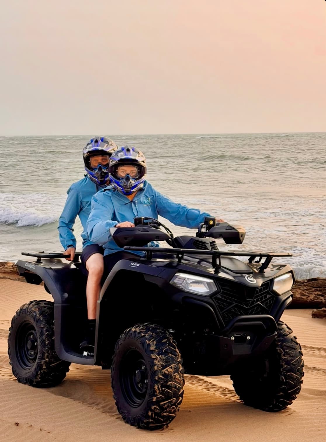 Two riders on a quad on the beach at golden hour