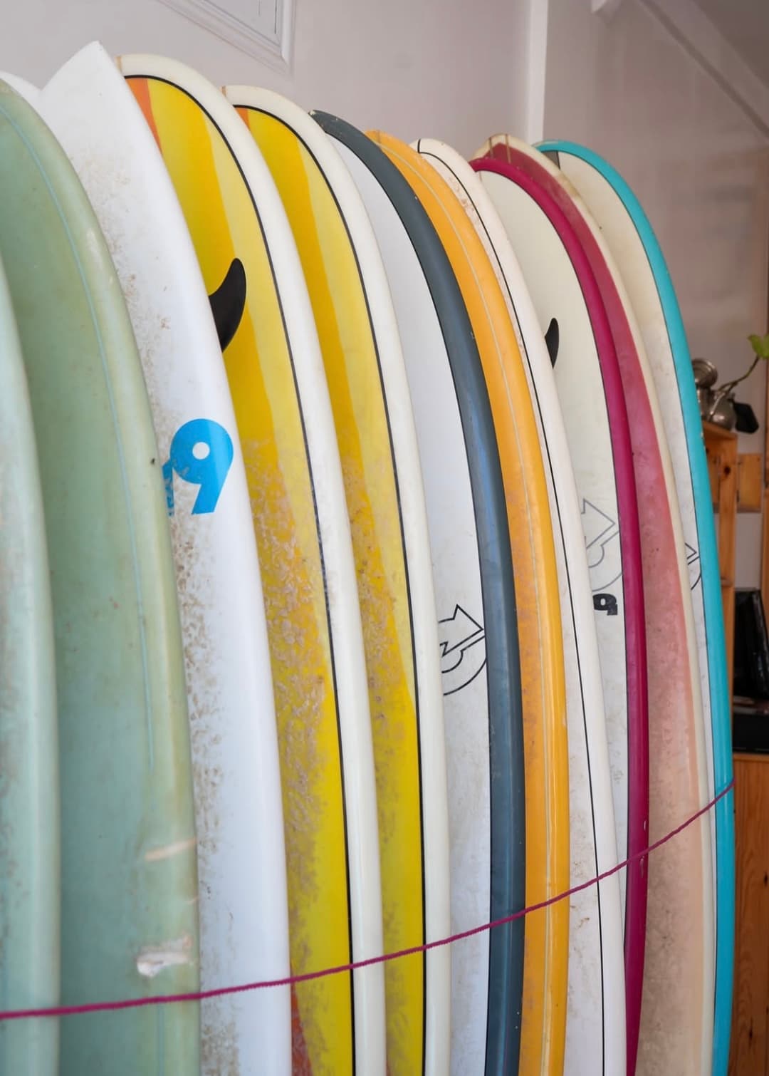 Rack of colourful soft-top surfboards
