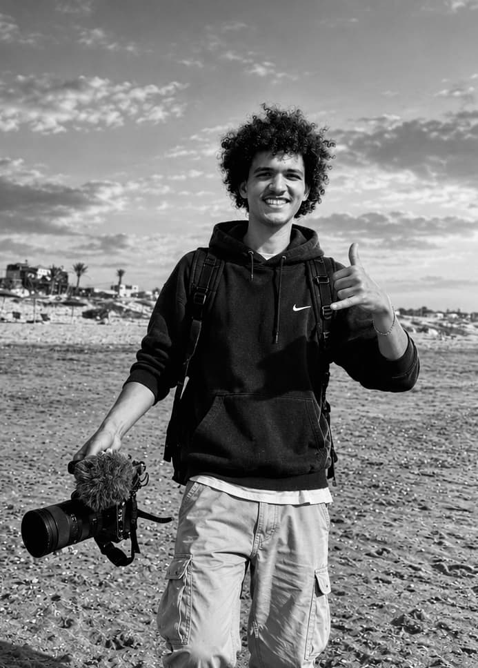 Younes, photographer and founder of Essaouira Adventures, smiling on the beach with his camera